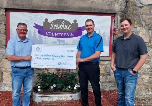 Three men posing for a photo with a check